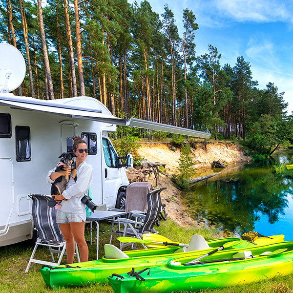 Girl standing holding her pet dog near the motorhome
